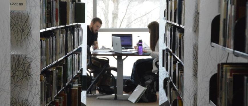 两位学生在QC图书馆3-9-16的桌子上学习